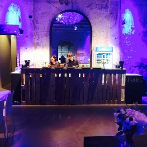 Blau und lila beleuchtete Eventlocation in Hamburg an der zwei Servicemitarbeiter das Catering zubereiten